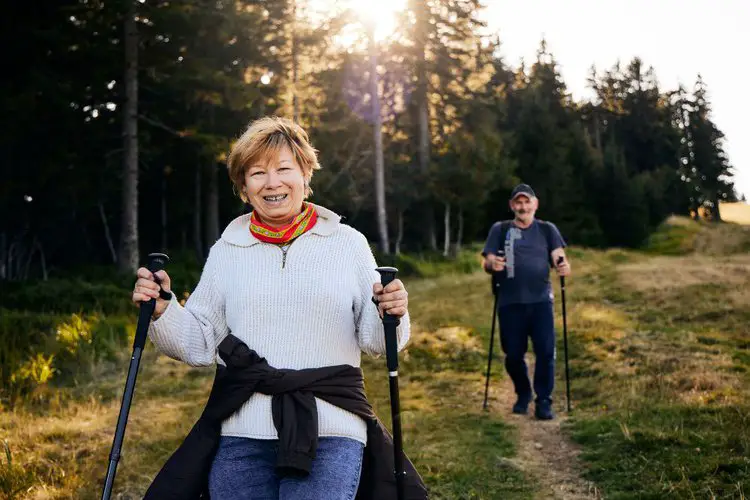 old woman and man uses hiking poles for support on their trip
