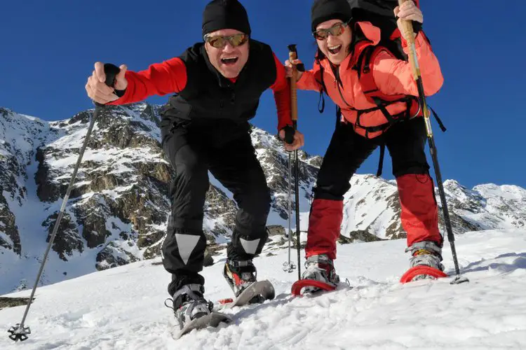 two people go hiking on snow using hiking poles with snow baskets