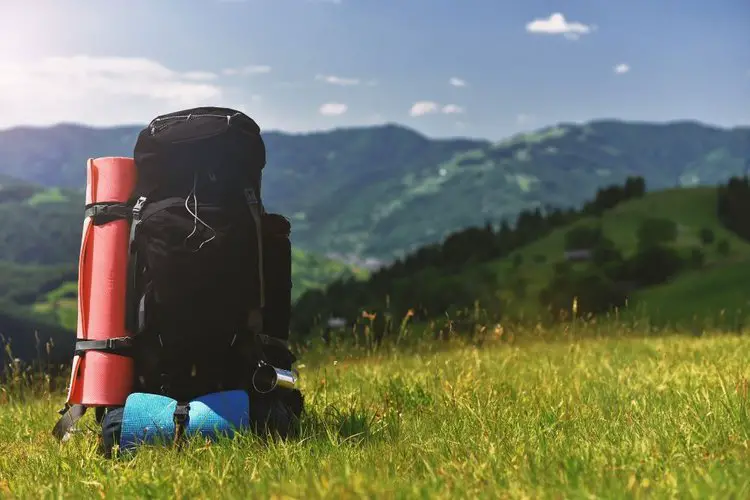 A hiking backpack and a sleeping bag attached on it, all of them are on the ground