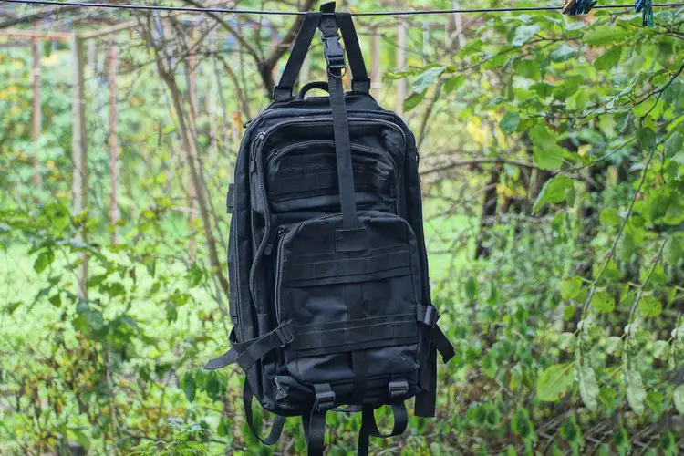 hang a black backpack on the rope between two trees