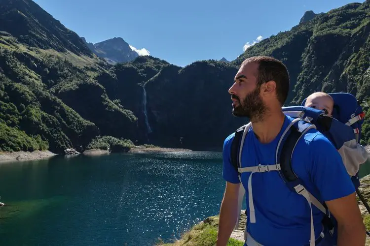 man buckles all the straps of his baby hiking backpack