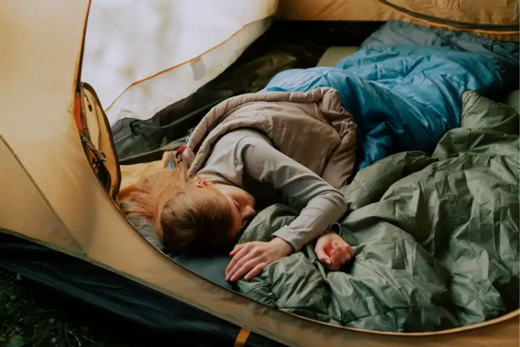 a girl sleeps tight in a tent after a hiking day