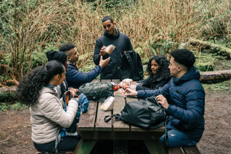 a group of friends is eating after a hike