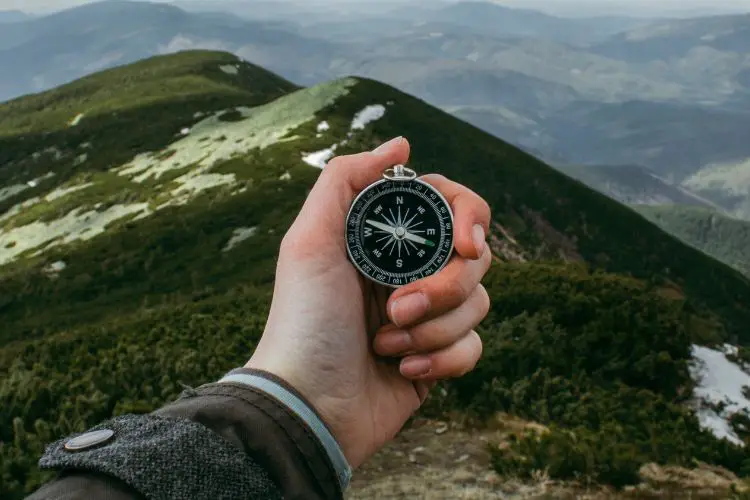 a man is using a compass in the mountain