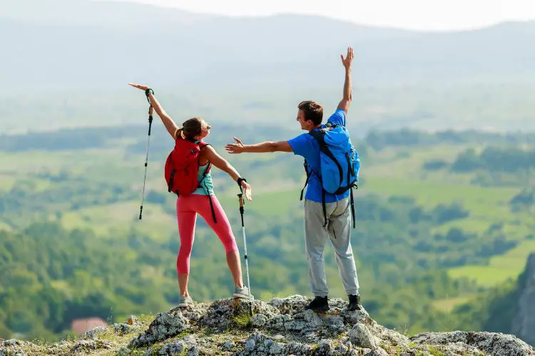 a woman wearing yoga pants is having fun while hiking with her boyfriend