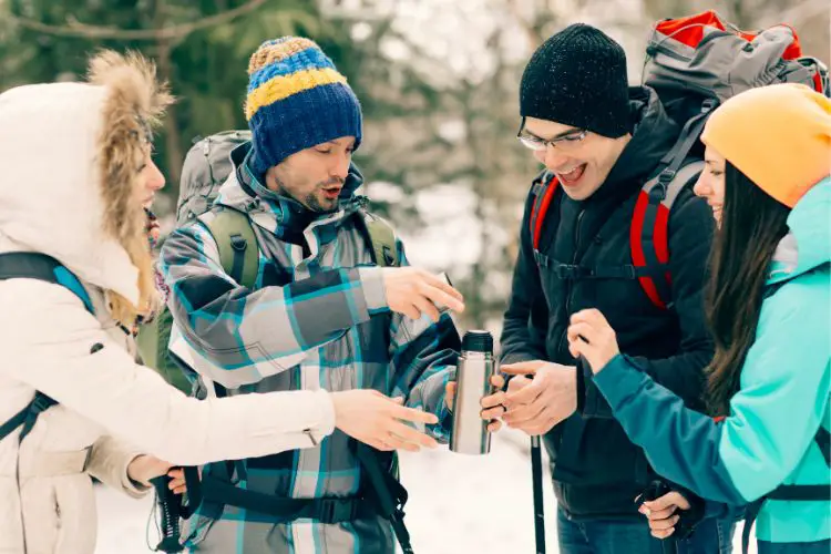 group of friends is drinking water in winter hike