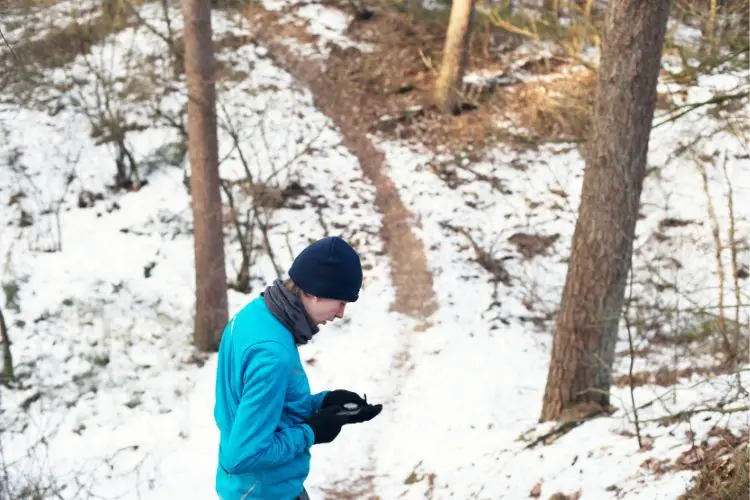 man using compass to navigate the direction in snowy terrain