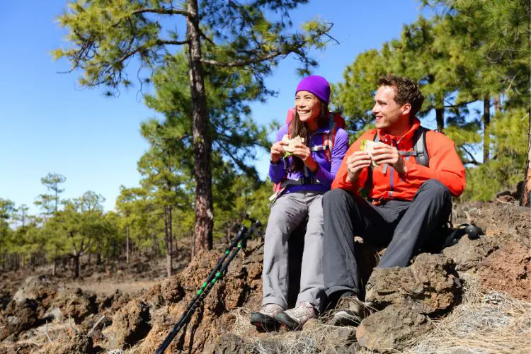 two people are eating while hiking