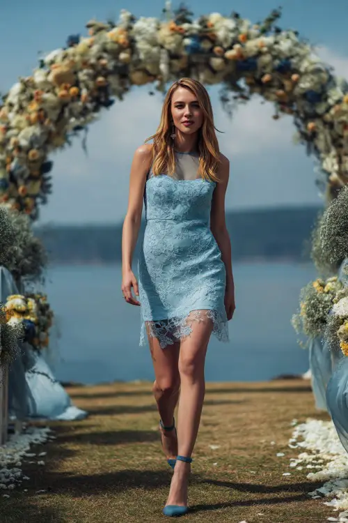A confident woman in a light blue lace cocktail dress with sheer detailing and ankle-strap heels, walking near a floral-covered wedding arch at an outdoor ceremony