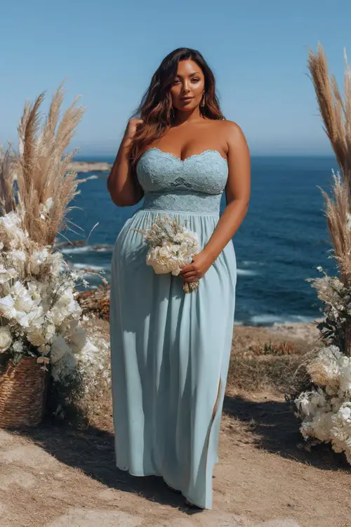 A plus-size woman in a soft blue midi dress with a sweetheart neckline and lace overlay, standing at a coastal wedding altar surrounded by sea grasses and white blooms 
