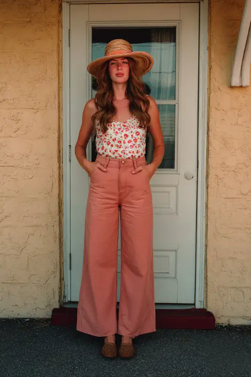 A midsize woman wears a printed sleeveless top paired with high-waisted wide-leg pants and a straw hat