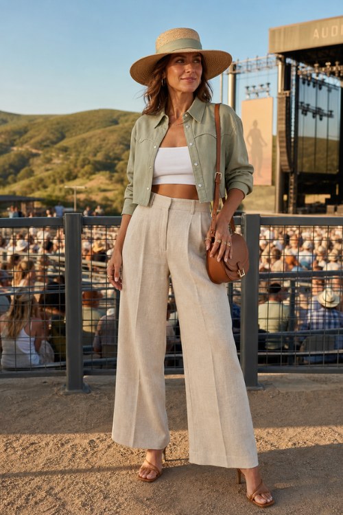 A woman over 30 wears a cropped western-style shirt in soft sage green with pearl snap buttons worn open over a fitted white bandeau, paired with wide-leg linen trousers, and strappy heeled sandal