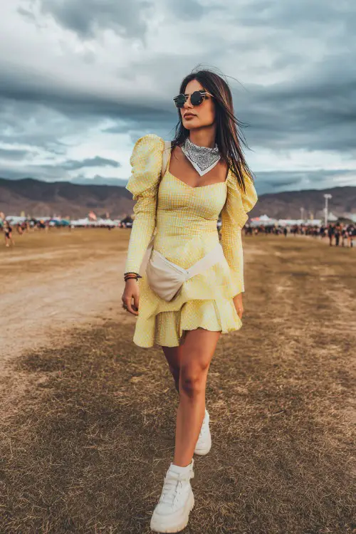 A woman wearing a ruffled mini dress with puff sleeves and clean white platform sneakers, carrying a belt bag and wearing a bandana around her neck 