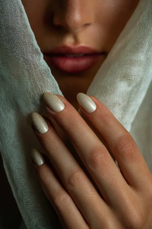 Bridal hand delicately lifting veil, sculpted almond-shaped acrylic nails in glossy ivory with fine gold glitter fade