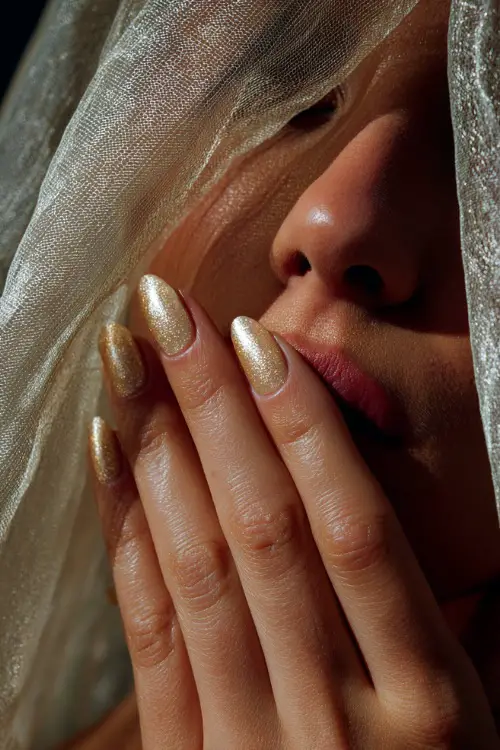 Bridal hand delicately lifting veil, sculpted almond-shaped acrylic nails in glossy ivory with fine gold glitter fade