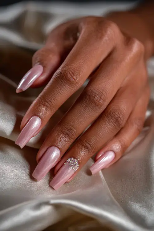 Bridal hand posing against a sheer curtain, extra-long coffin-shaped acrylic nails in pale pink with crystal bead clusters along the tips 