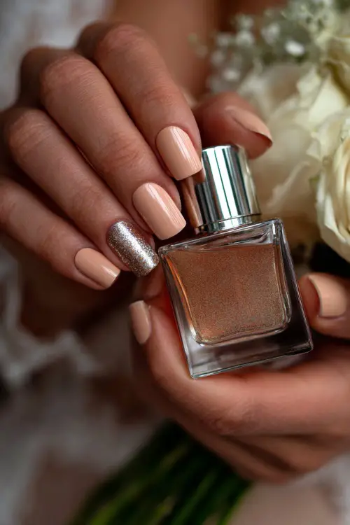 Bride holding a rose gold perfume bottle, square nails in soft rose beige with silver flake accent on middle finger