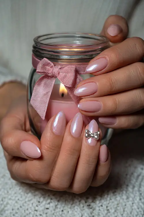 Bride holding candlelight jar, almond-shaped nails in pastel pink with pearl shimmer and one 3D bow charm on the ring finger