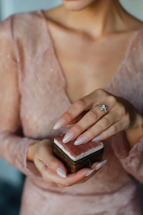 Bride holding vintage ring box, long almond nails in sheer peach with subtle glitter fade and crystal cuticle accents 