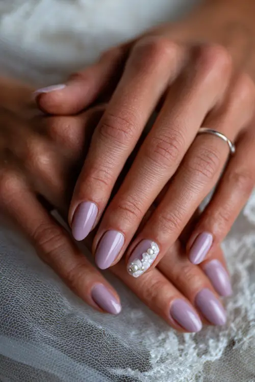 Bride’s fingers gently placed on veil, almond nails in soft lavender with one accent nail in floral design and pearl bead 