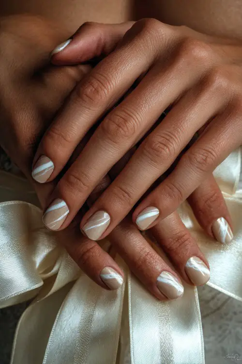 Bride’s fingers wrapped around satin ribbon, almond nails in creamy ivory with white swirl detailing and clear gloss overlay