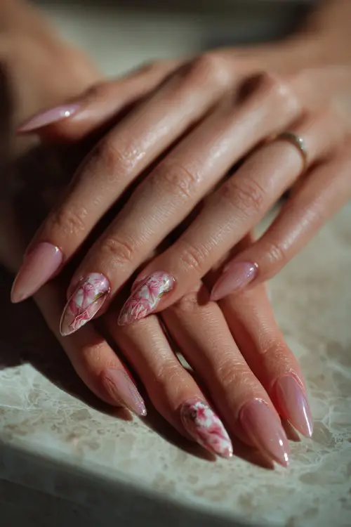 Bride’s hands resting on a vanity table, long stiletto nails with translucent pink polish and 3D floral appliqué, soft light background 