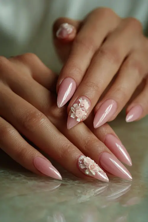 Bride’s hands resting on a vanity table, long stiletto nails with translucent pink polish and 3D floral appliqué, soft light background 