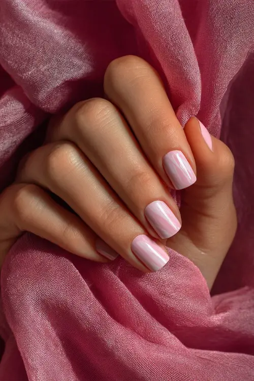 Bridesmaid’s hand against a soft chiffon ribbon, short ballerina nails in warm dusty rose with one nail in transparent white swirl design 