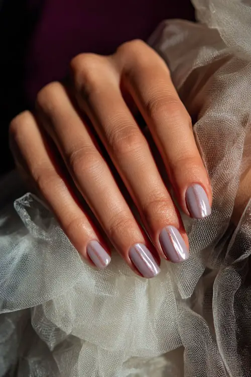 Bridesmaid’s hand beside a soft tulle dress, milky lavender almond nails with a glossy top and diagonal rose-gold stripe 