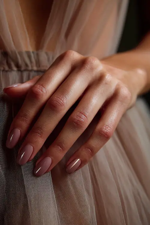 Bridesmaid’s hand beside a soft tulle dress, milky lavender almond nails with a glossy top and diagonal rose-gold stripe 