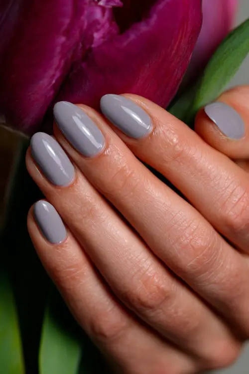 Bridesmaid’s hand brushing a tendril of hair, medium-length almond nails in soft gray-lavender with glossy finish and silver micro line across the middle 