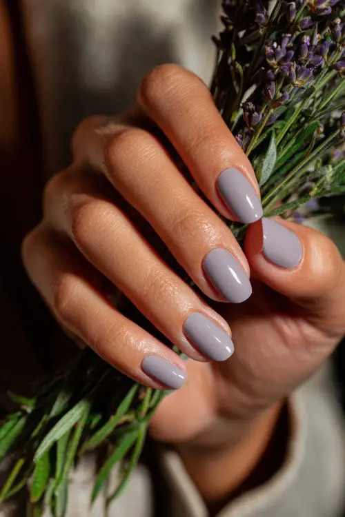 Bridesmaid’s hand brushing a tendril of hair, medium-length almond nails in soft gray-lavender with glossy finish and silver micro line across the middle 