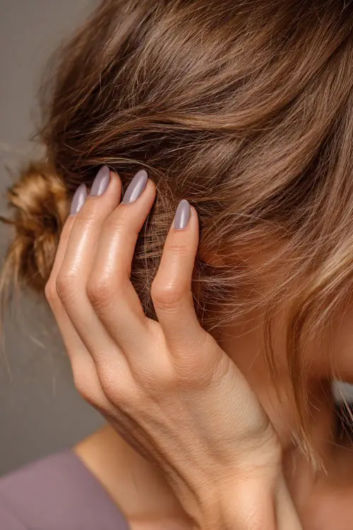 Bridesmaid’s hand brushing a tendril of hair, medium-length almond nails in soft gray-lavender with glossy finish and silver micro line across the middle