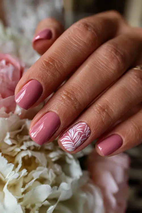 Close-up of bridal hand beside soft floral décor, short square nails in matte pastel pink with delicate white line art on one nail