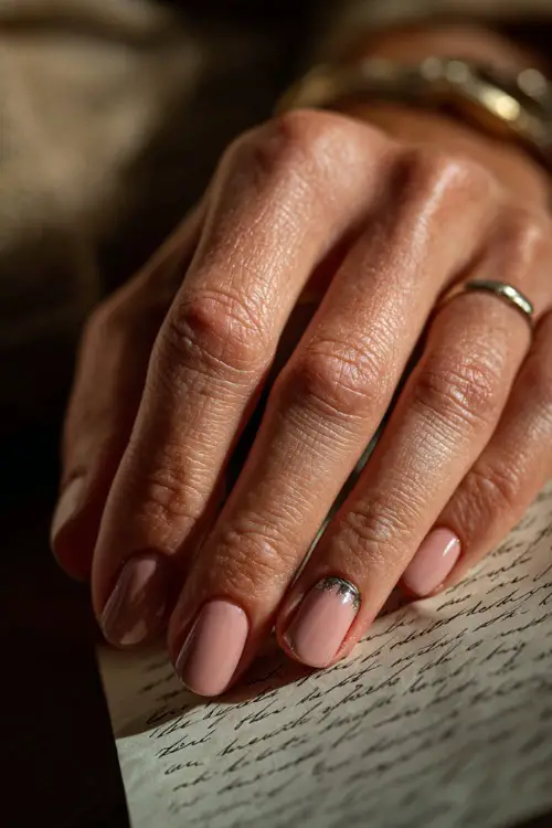Close-up of hand holding handwritten vows, short soft pink nails with a chrome accent on the middle finger, romantic warm lighting