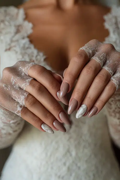 Elegant close-up of a bride holding lace gloves, featuring glossy ballerina nails in neutral beige with marble accent on middle fingers