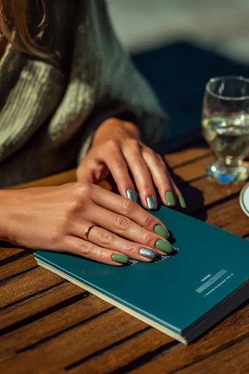 Guest holding a menu card at an outdoor table, short square nails in matcha green with silver striping tape on two fingers 