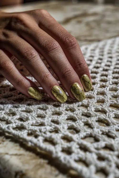 Guest’s hand resting on a white crochet table runner, short nails in pistachio green with marble texture and chrome shimmer 