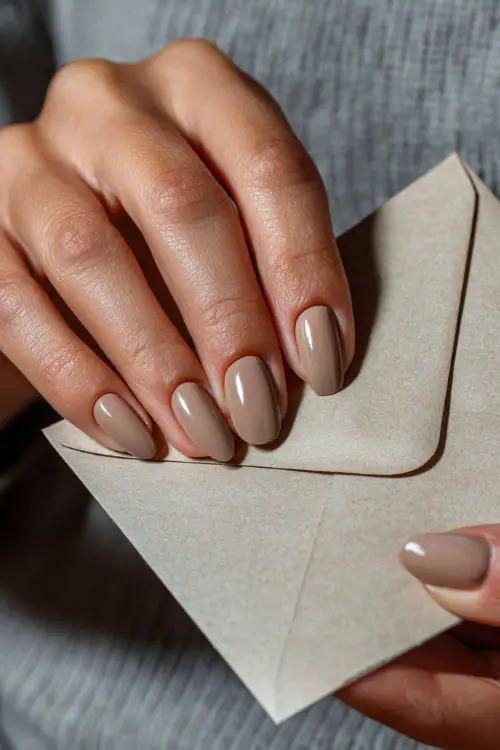 Hand of bride placing a letter in envelope, almond nails in light beige with chrome French tips and clear glossy coat
