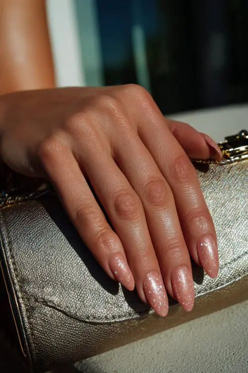 Hand placed on bridal clutch, almond nails in rose gold shimmer with glossy overlay and tiny silver foil fragments 