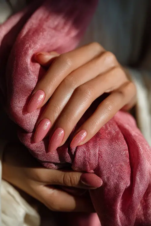 Hand tying a silk scarf, almond-shaped nails in translucent pink with gold foil flakes on ring fingers, soft summer lighting in background 