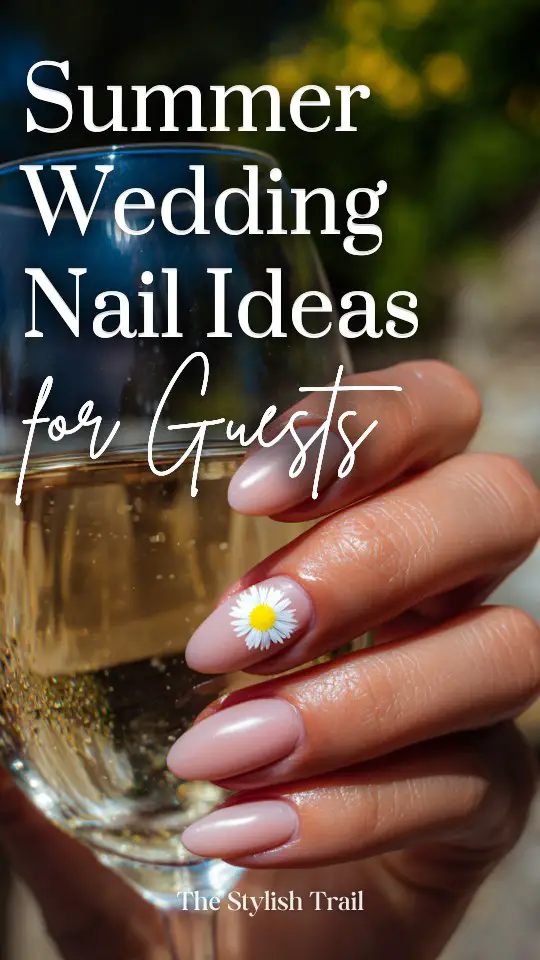 Hand with glossy nude pink nails holding a glass of white wine, featuring a daisy flower design