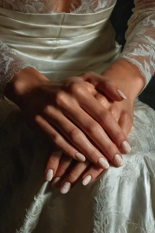 ridal hands crossed on lap in a silk gown, medium oval nails in creamy ivory polish with one accent nail in lace texture