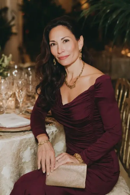 A woman over 50 wears a burgundy long-sleeved column dress with subtle ruching at the waist