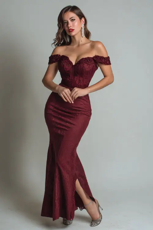 A woman wears a wine-red off-shoulder gown with lace details and a fishtail hem, paired with crystal earrings and metallic heels for a dramatic evening look 
