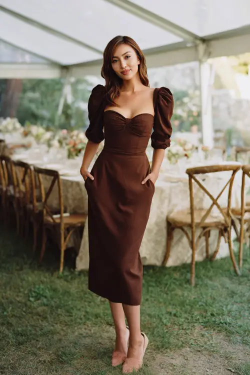 Woman wearing a chocolate brown midi dress with a sweetheart neckline and three-quarter sleeves, styled with ankle strap heels