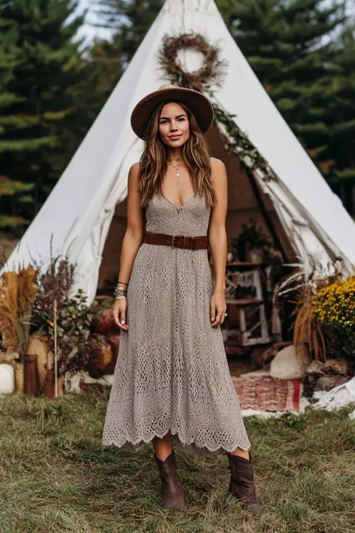 Woman wearing a taupe crochet boho midi dress with scalloped hem, accessorized with a brown leather belt and ankle boots, standing in front of a teepee-style wedding altar 