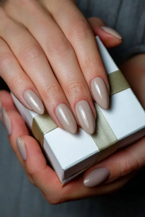 Almond-shaped warm beige nails with a smooth matte finish, guest holding a wedding favor box 