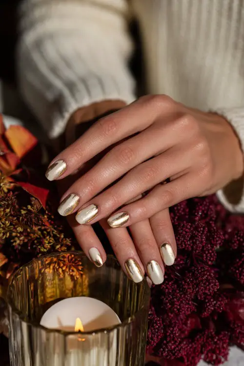 Cream-colored nails with gold foil half-moon design, bride holding a candlelit centerpiece with autumn décor