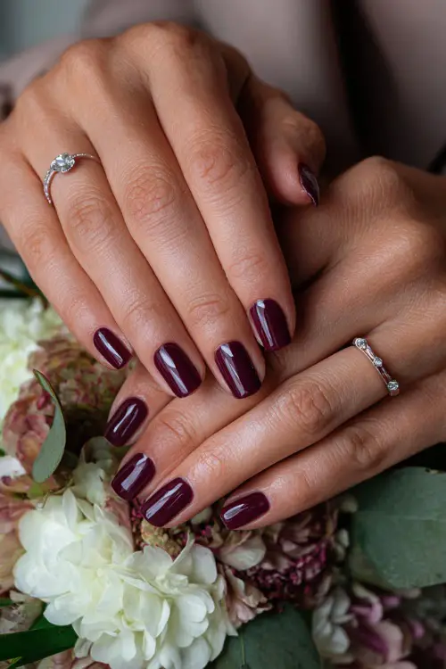 Dark plum glossy nails with rhinestone accents, bridesmaid’s hands adjusting a silk ribbon bouquet 